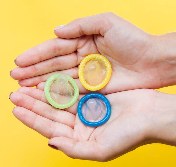 close-up-manos-sosteniendo-condones-espacio-copia_23-2148259682